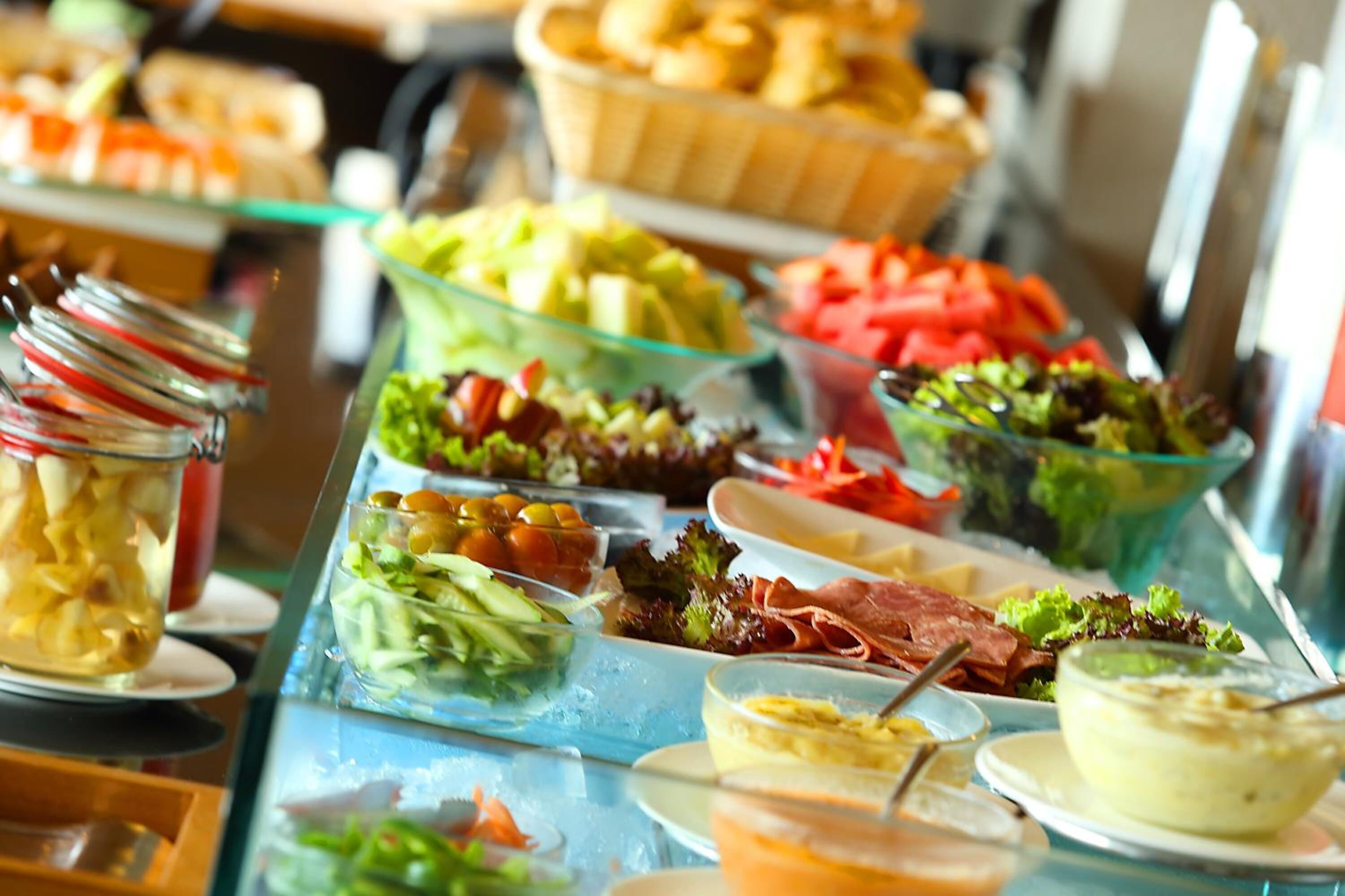 Un buffet proposant une variété de plats, notamment des salades, des fruits et des sauces.