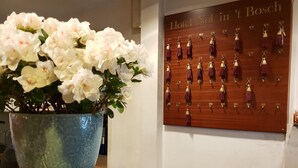 A reception area with a blue vase of white flowers, a wooden key display, and a bell on a wooden base. - Nol in 't Bosch (Wageningen)