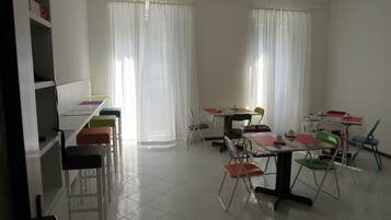 Ein Klassenzimmer mit weißen Wänden, einer Tafel und einem Schreibtisch mit Stühlen.