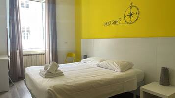 Una camera d'hotel con un letto, un comodino, una sedia e una finestra con tende.