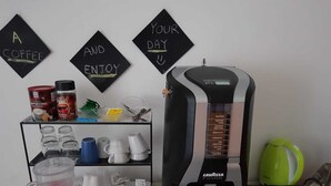 A coffee machine with a menu, coffee cups, and a coffee grinder on a table. - Smart Rooms (Trieste)