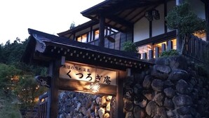 A traditional Japanese building with a stone wall entrance and a wooden structure above.