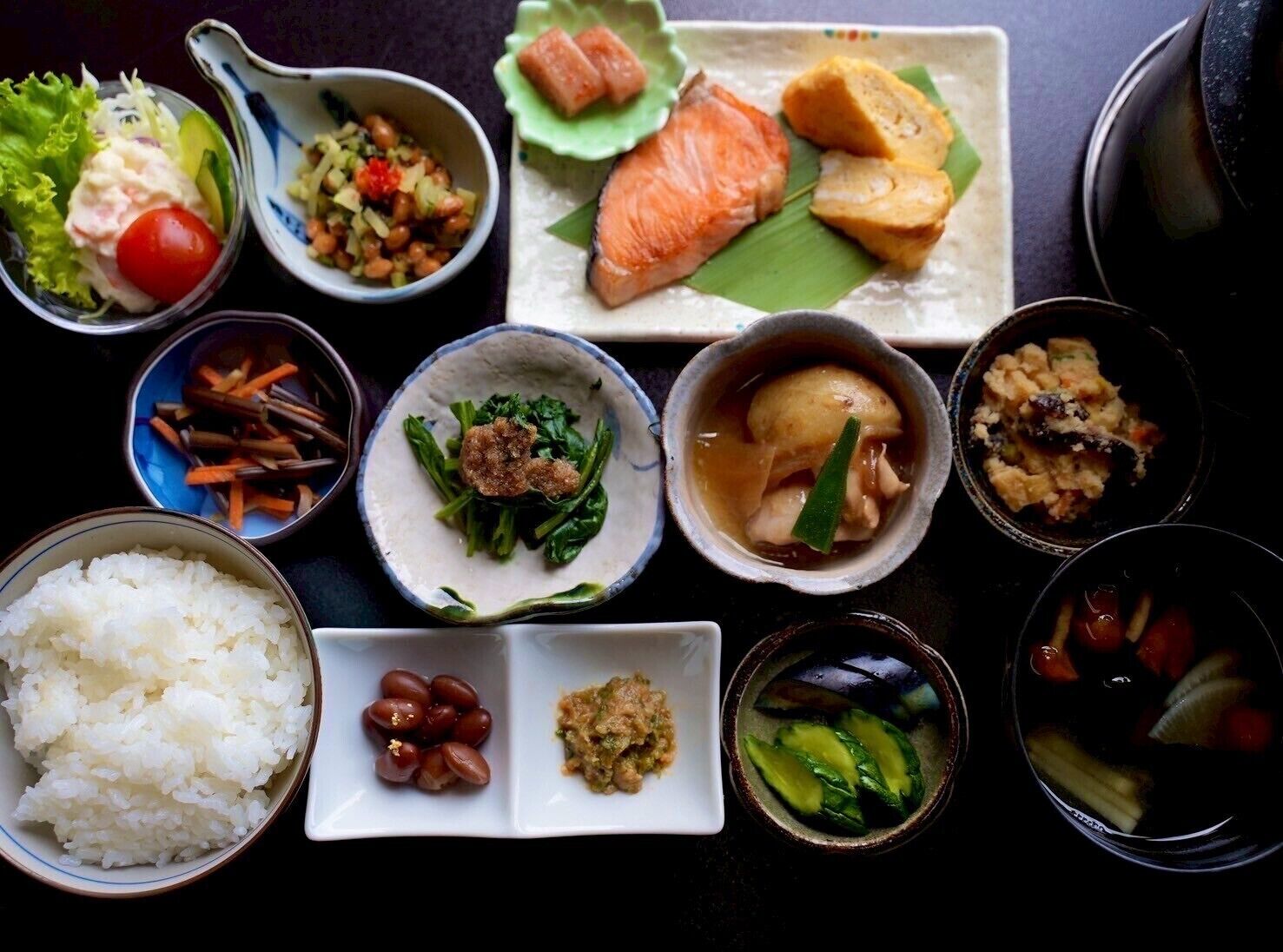 Diversos pratos com arroz, legumes e peixe, dispostos sobre uma mesa.