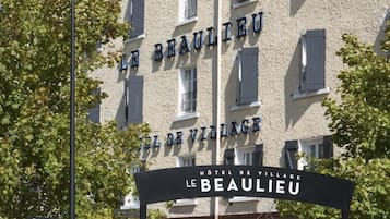 A hotel named "Le Beaulieu" with outdoor seating and a sign indicating "CANAL+ CANAL SATELLITE".