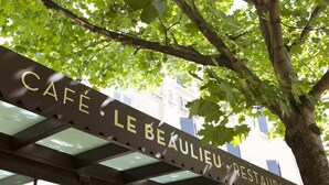 A café sign with the name "CAFÉ LE BEAULIEU RESTAURANT" under a tree. - Hôtel Le Beaulieu (Charbonnieres-les-Bains)