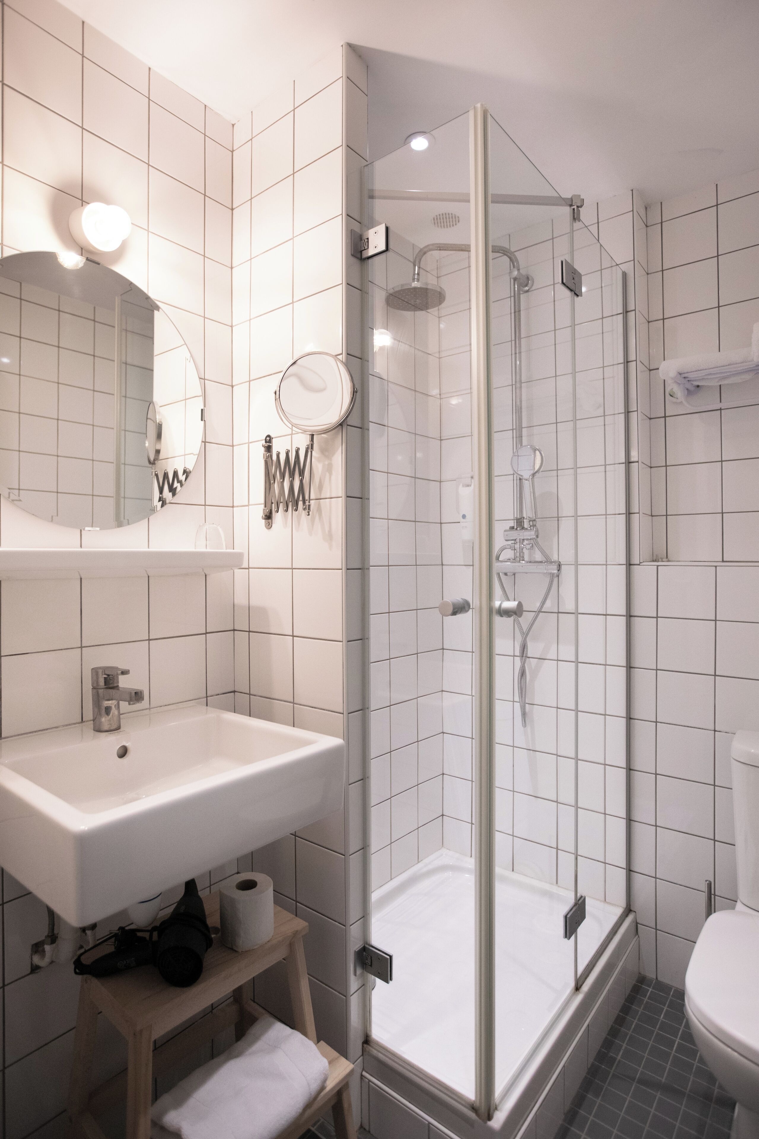 A modern bathroom with a glass-enclosed shower, a white sink, and a mirror above it.