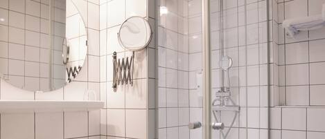A modern bathroom with a glass-enclosed shower, a white sink, and a mirror above it.