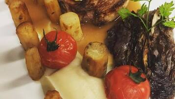 Un plato de comida con un filete, patatas asadas, tomates y puré de patatas.