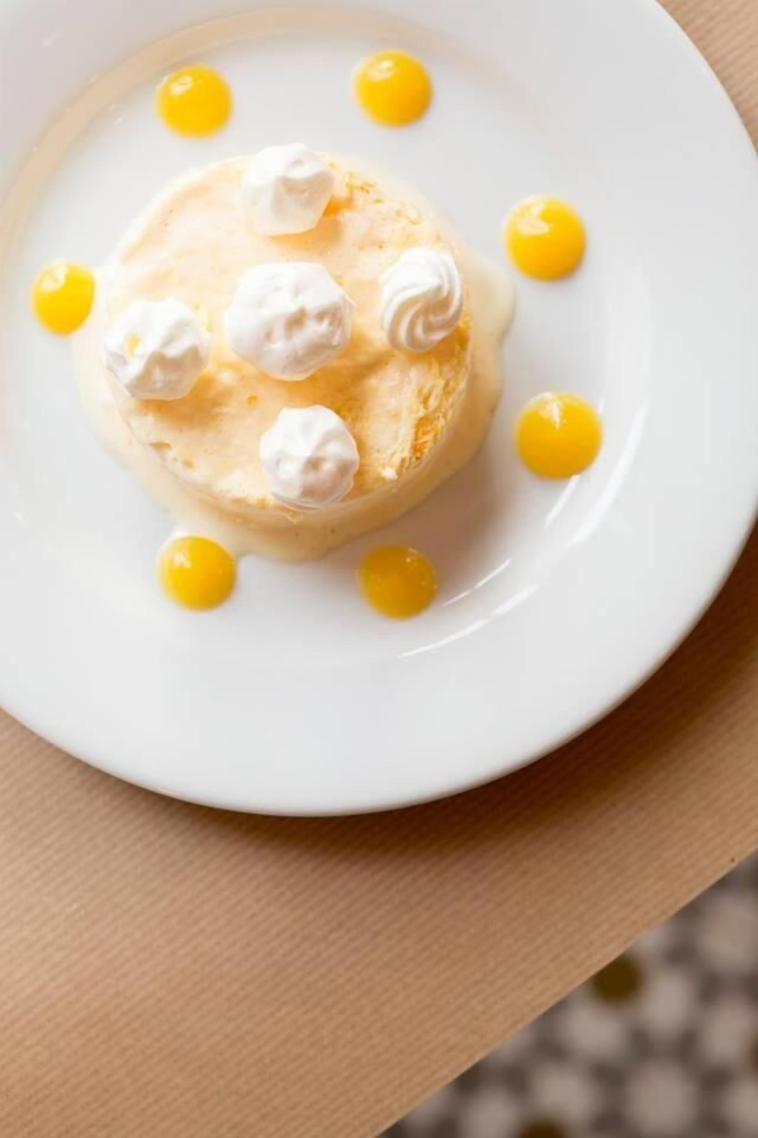 A dessert on a white plate with whipped cream and yellow sauce.