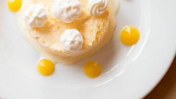 Un dessert su un piatto bianco, con panna montata e salsa gialla.