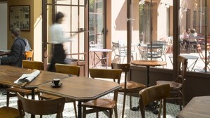 An indoor dining area with wooden tables and chairs, large windows, and hanging light fixtures. - Hôtel Le Beaulieu (Charbonnieres-les-Bains)