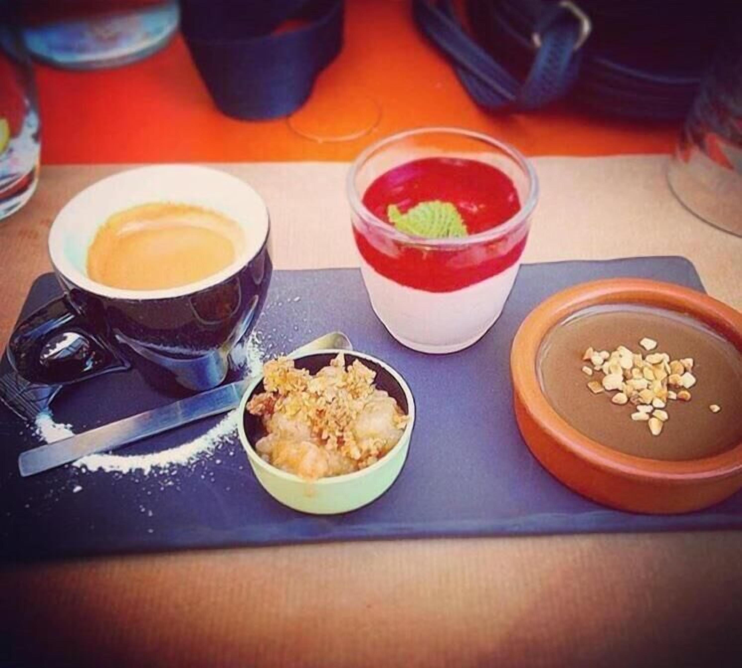 A dessert tray with various items including a bowl of soup, a red dessert, a bowl of rice with nuts, and a chocolate dessert.