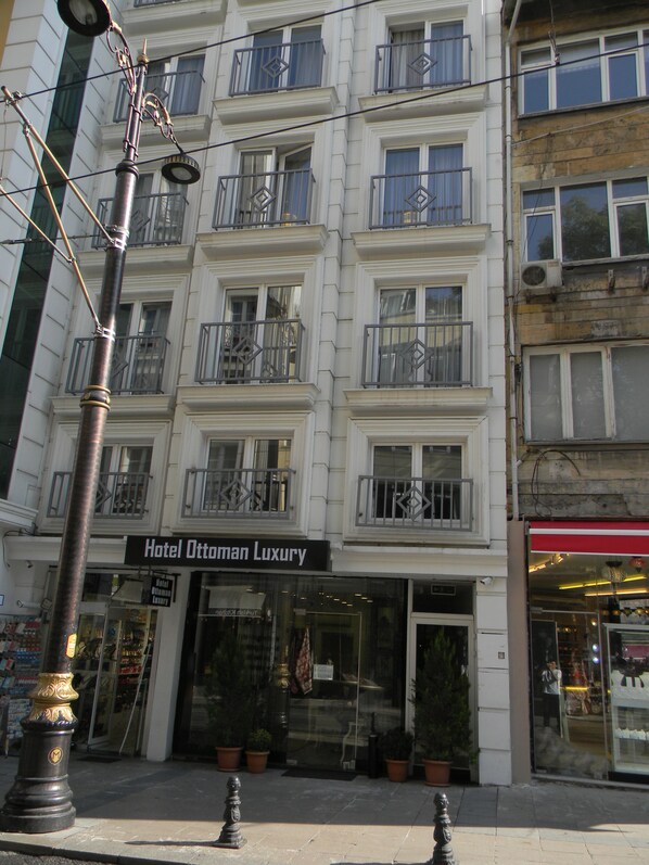 A building with a sign for Hotel Ottoman Luxury. It has multiple balconies with metal railings and a traditional architectural style.