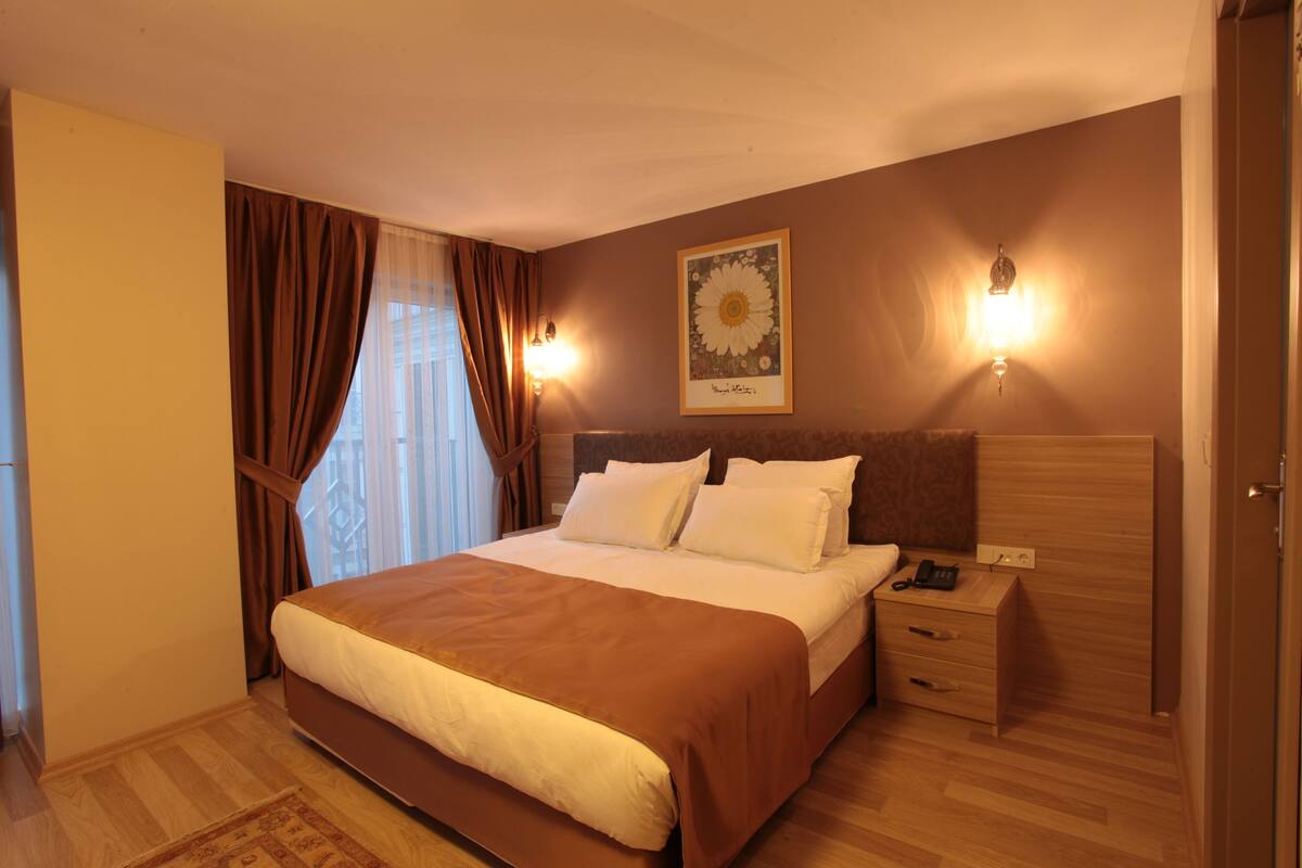 Une chambre d’hôtel avec un grand lit, une table de chevet avec une lampe et une œuvre d’art accrochée au mur.