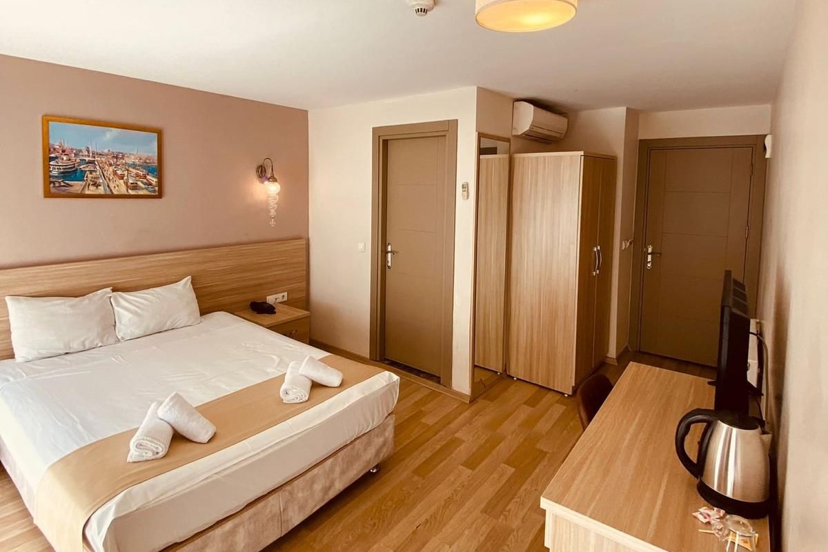 Une chambre d’hôtel avec un lit, un bureau, une chaise, une machine à café et un tableau au mur.
