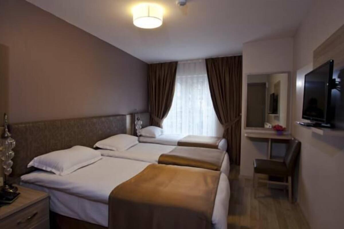 Une chambre d’hôtel avec deux lits, un bureau avec une chaise, une télévision et un miroir.