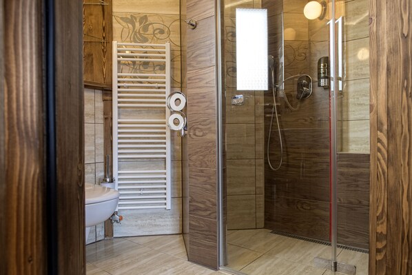 A modern bathroom with a glass shower enclosure, a white sink, and a towel rack. - Grand Hotel Bachledka Strachan (Zdiar)