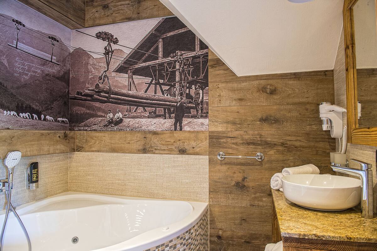 Une salle de bain avec une grande baignoire, des murs en bois, un plafond en bois et une photographie d’époque accrochée au mur.