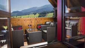 A balcony with wicker furniture, a wooden floor, and a view of mountains. - Wellness Penzión Strachan (Zdiar)