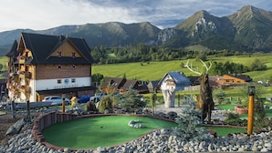 A mountain lodge with a restaurant, a golf course, and a large deer statue. - Wellness Penzión Strachan (Zdiar)