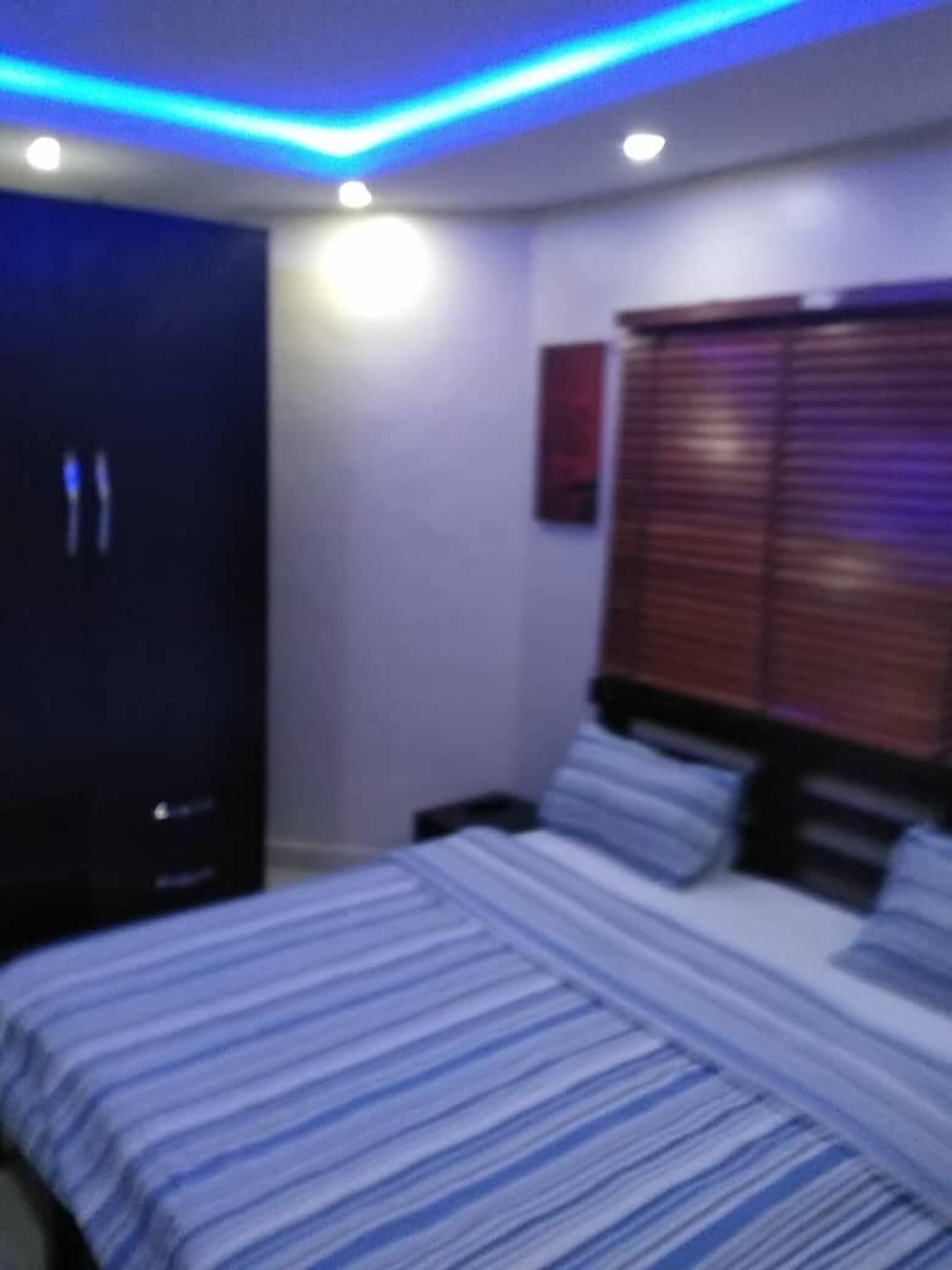 A bedroom with a bed, a TV, and a window with blinds.