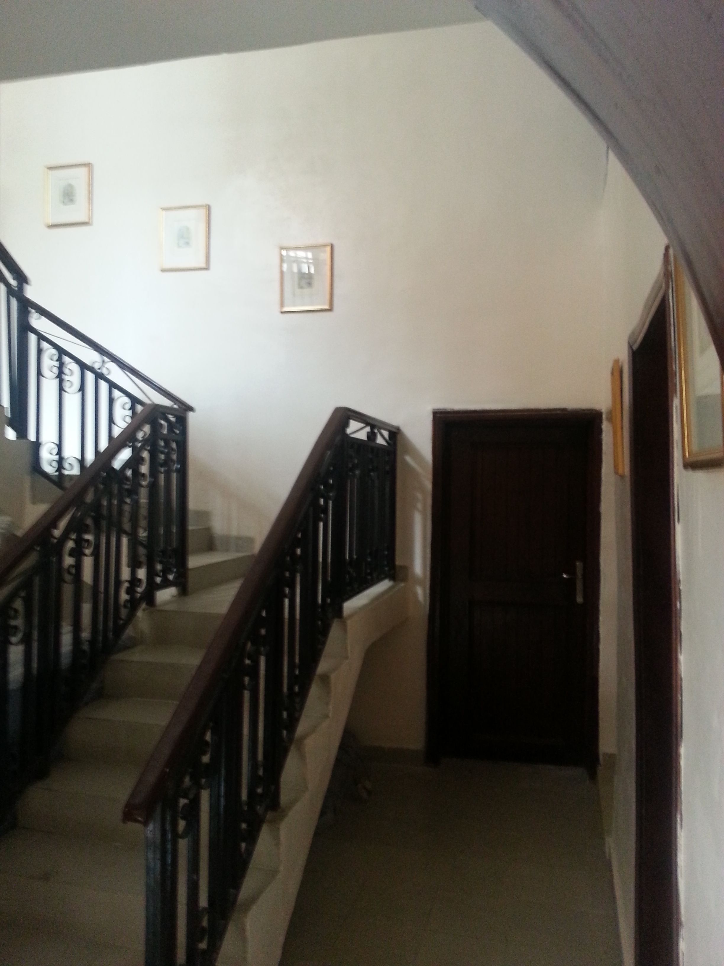 A staircase with a wooden handrail and black balusters, leading to a dark wooden door.