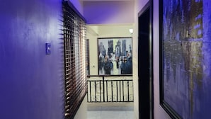 A hallway with a modern design, featuring a blue-lit ceiling, a large framed cityscape painting, and a metal railing. - Preserve Hotel Lekki Phase 1 (Lekki)