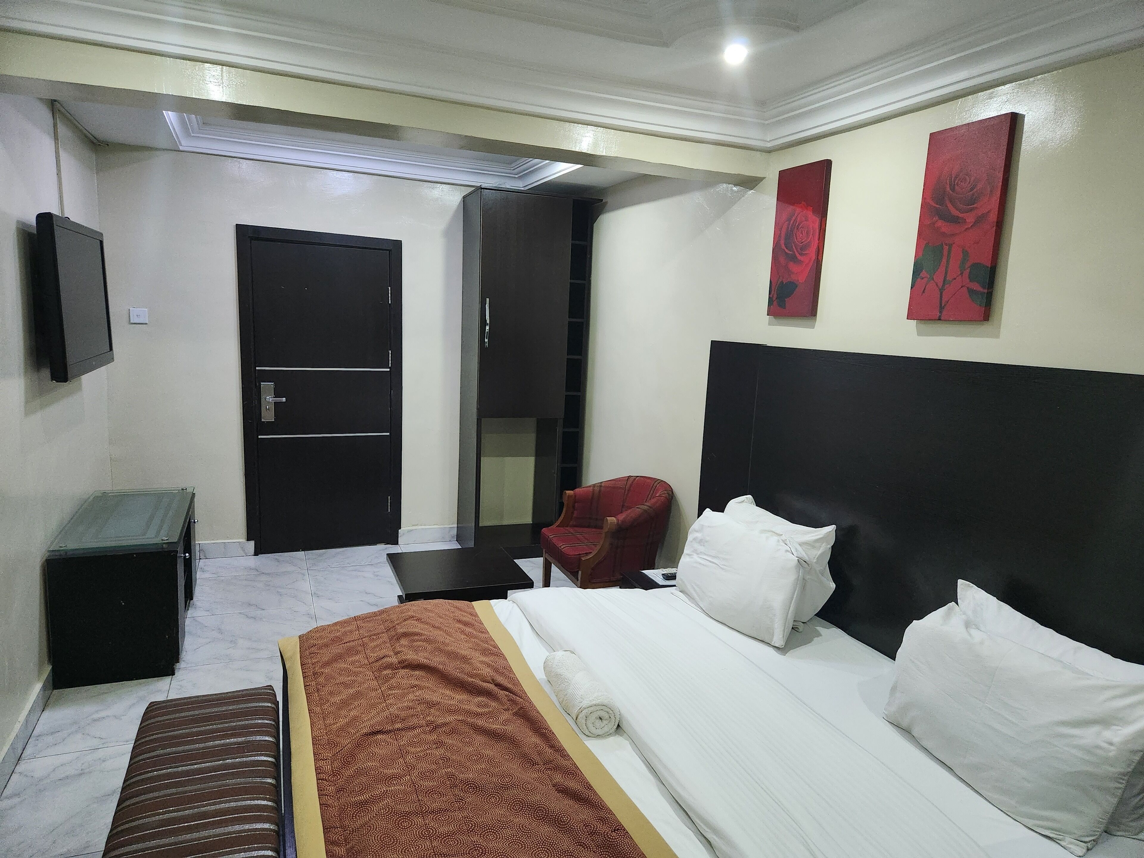 A hotel room with a bed, a chair, a desk, and a TV.