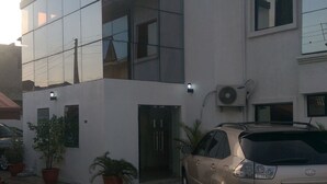 A modern two-story building with a paved courtyard, a parked car, and potted plants. - Preserve Hotel Lekki Phase 1 (Lekki)