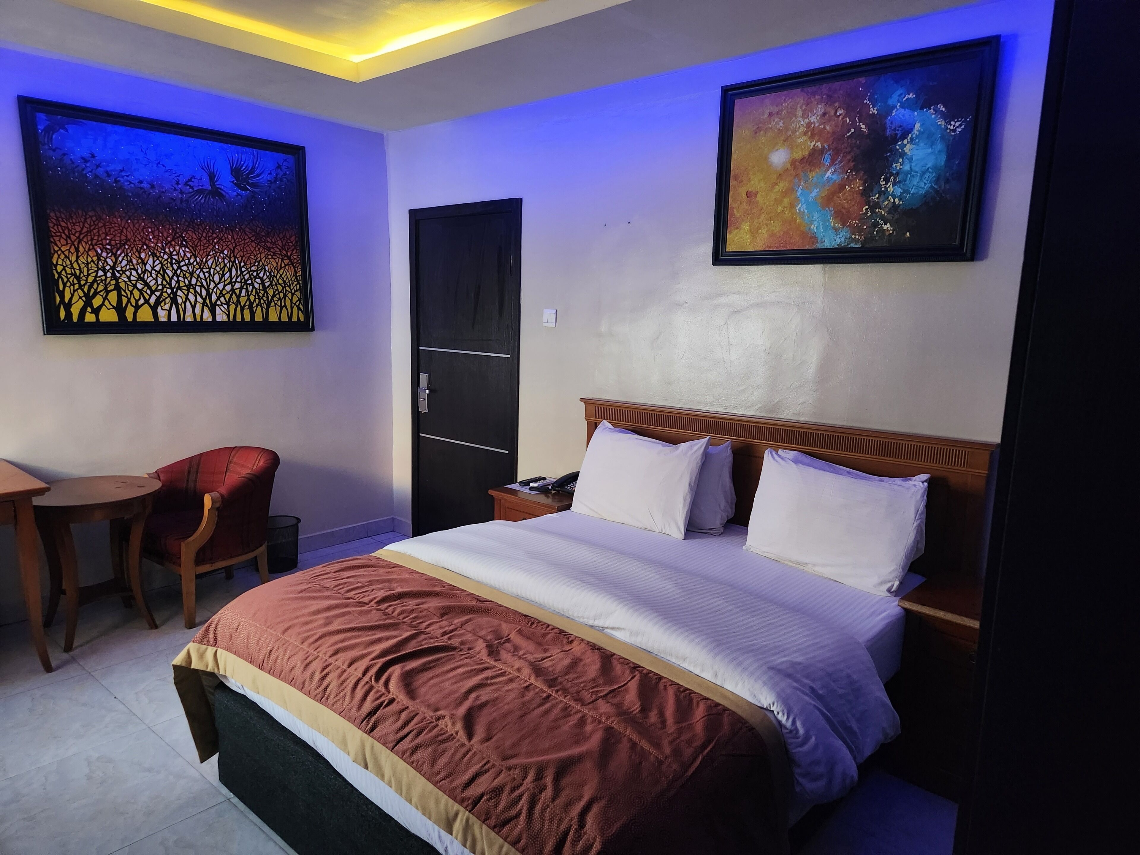 Camera d'albergo con un letto, una scrivania e due poltrone. Alle pareti si vedono due quadri.