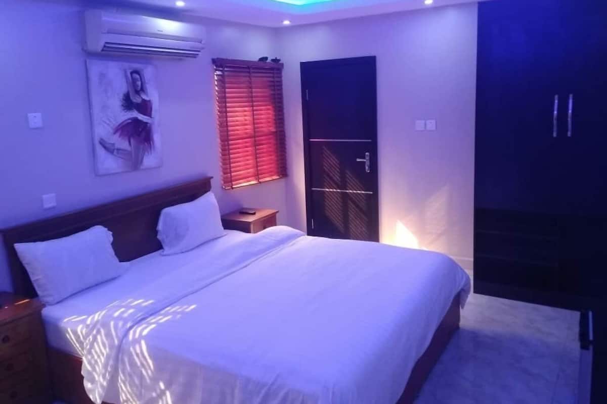 A bedroom with a bed, bedside tables, a wardrobe, and a window with blinds.