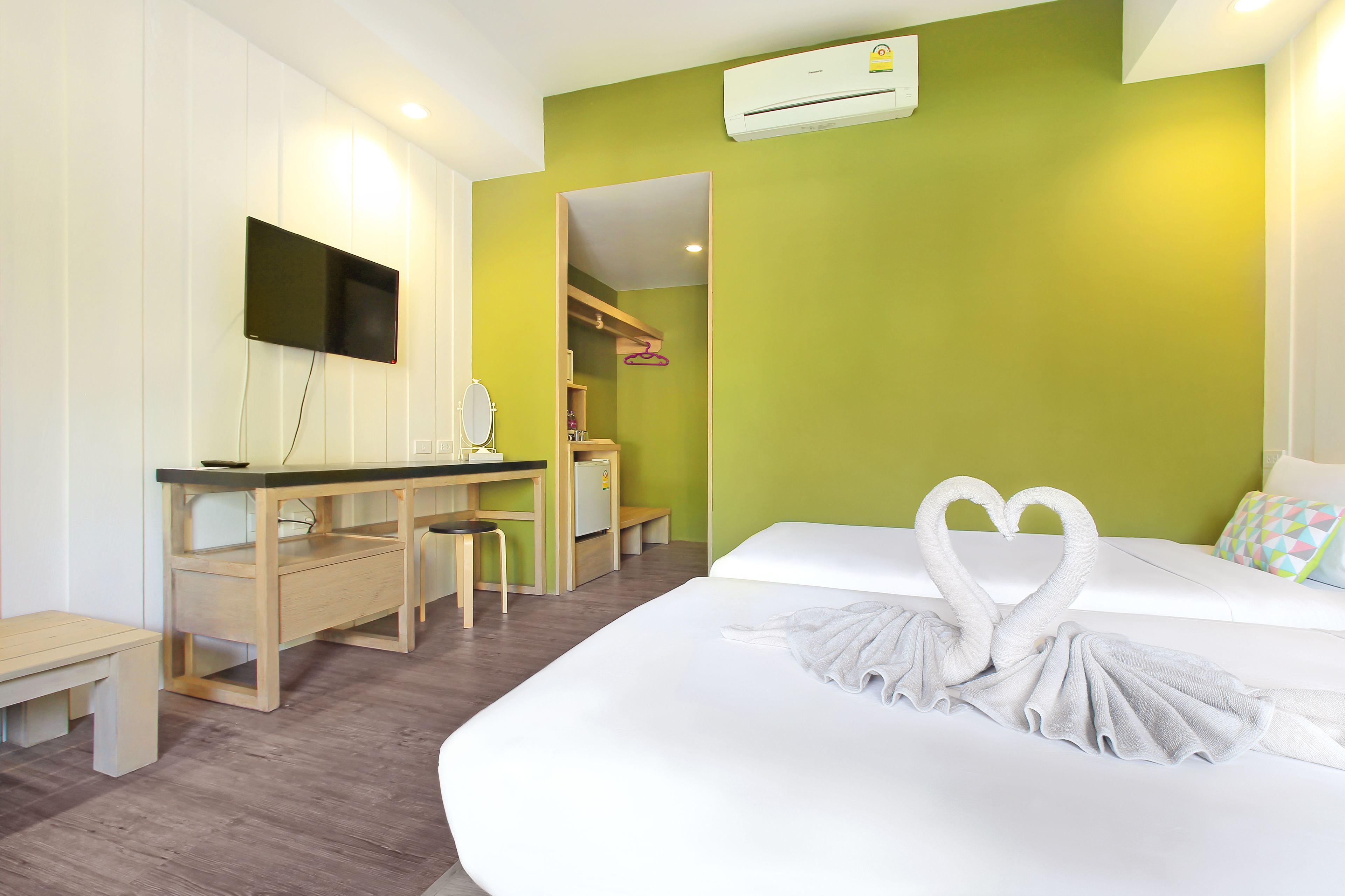 A hotel room with a bed, a desk, a chair, and a TV mounted on the wall.