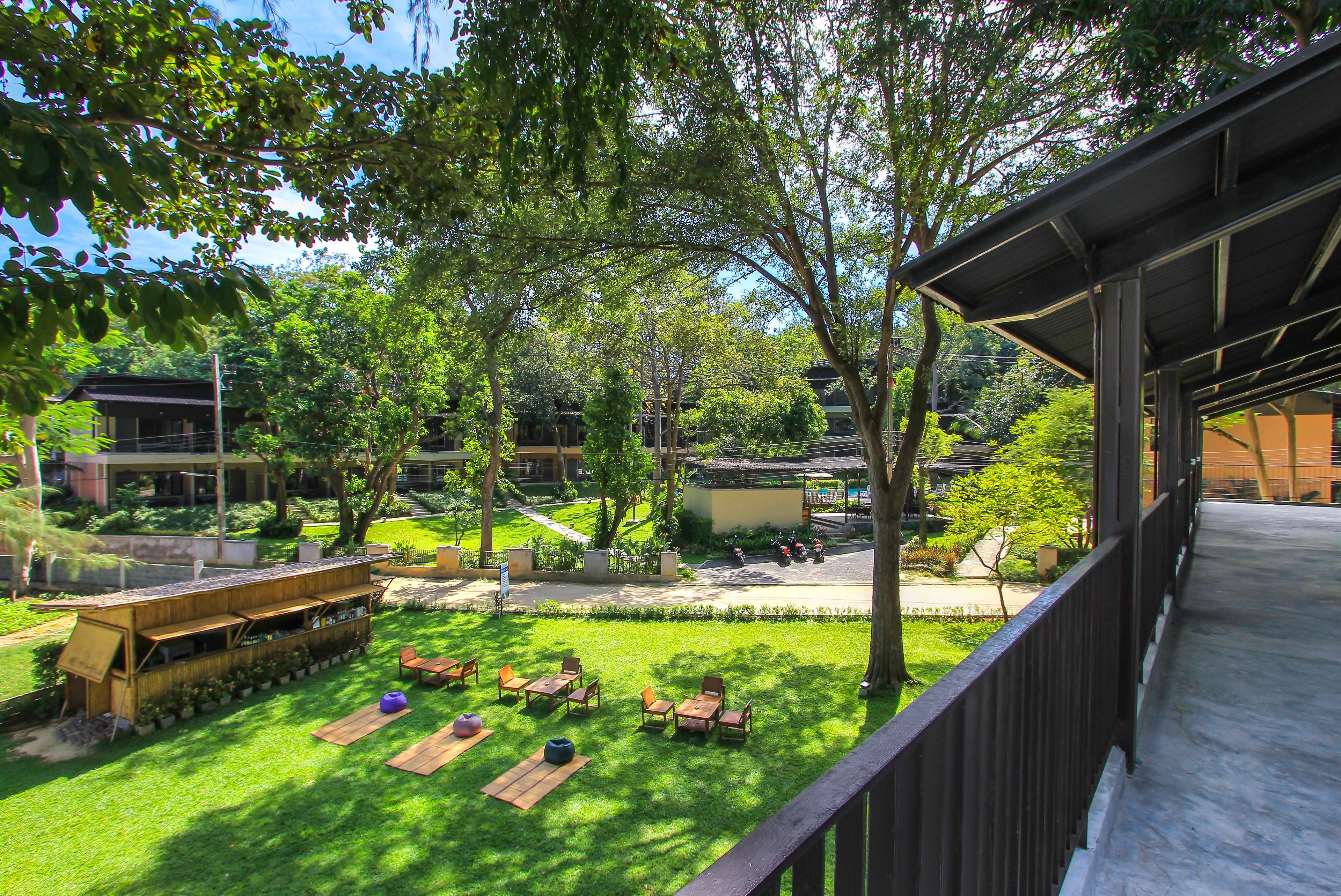 A courtyard with outdoor seating, trees, and a building with a covered walkway.