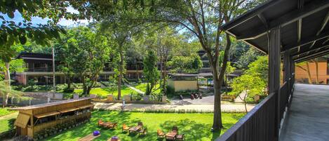 A courtyard with outdoor seating, trees, and a building with a covered walkway.