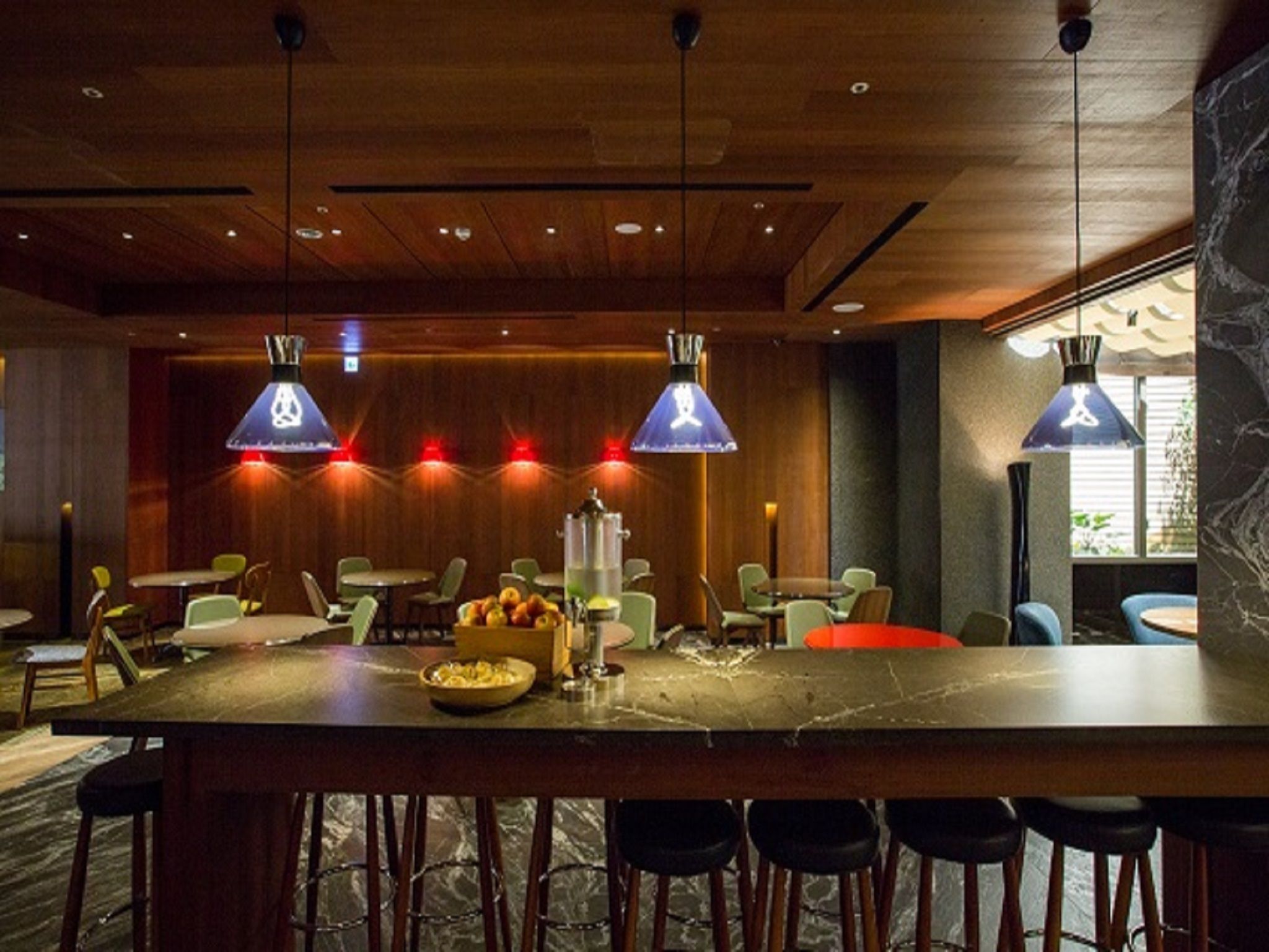 A modern bar area with wooden ceiling, pendant lighting, and bar stools.