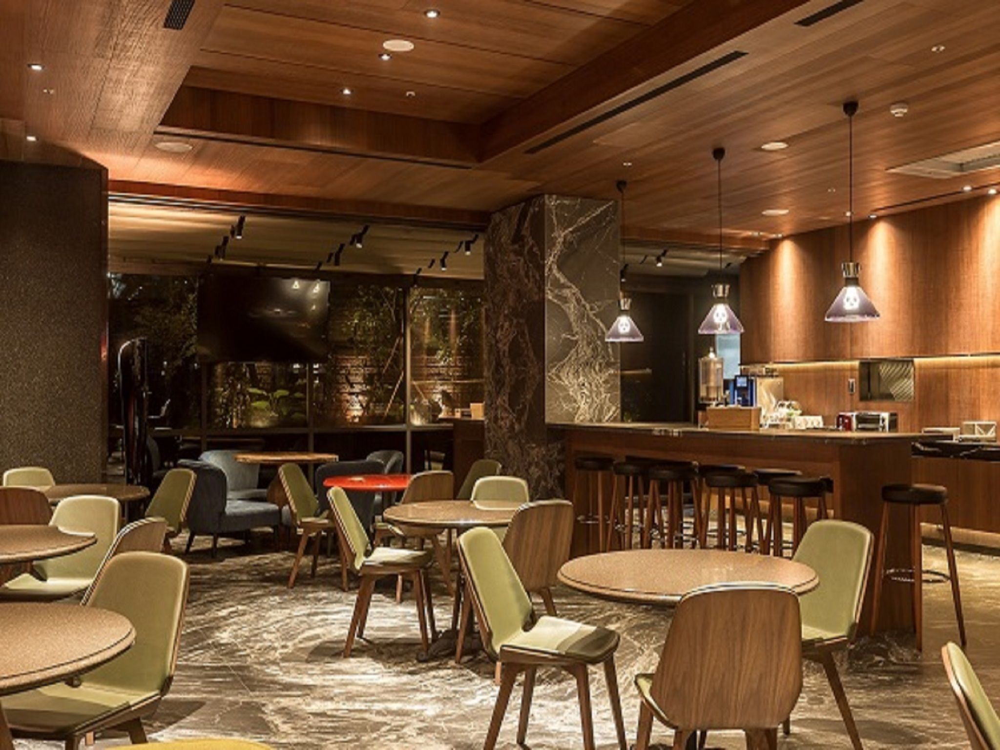 Een modern interieur met ronde tafels en stoelen, een bar en uitzicht op het omliggende landschap.