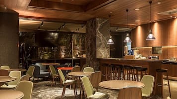 Een modern interieur met ronde tafels en stoelen, een bar en uitzicht op het omliggende landschap.