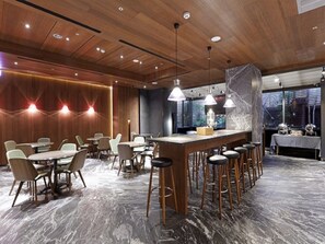 Un comedor moderno con paneles de techo de madera, iluminación colgante, suelo de mármol y una barra con taburetes.