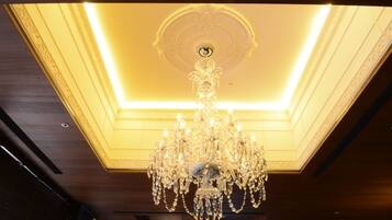 A chandelier with multiple arms and crystal decorations hanging from a ceiling with a recessed light.