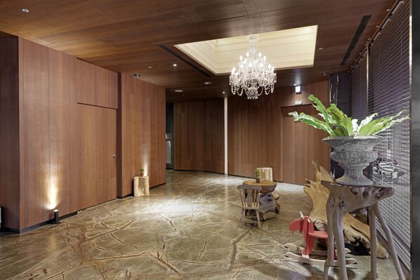A spacious hallway with wooden walls and a stone floor, a chandelier, and a small table with a plant. - Inhouse Hotel Taichung (Taichung)