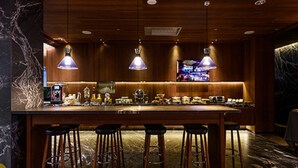 Una zona de bar con paneles de madera, suelo de mármol y varios taburetes.