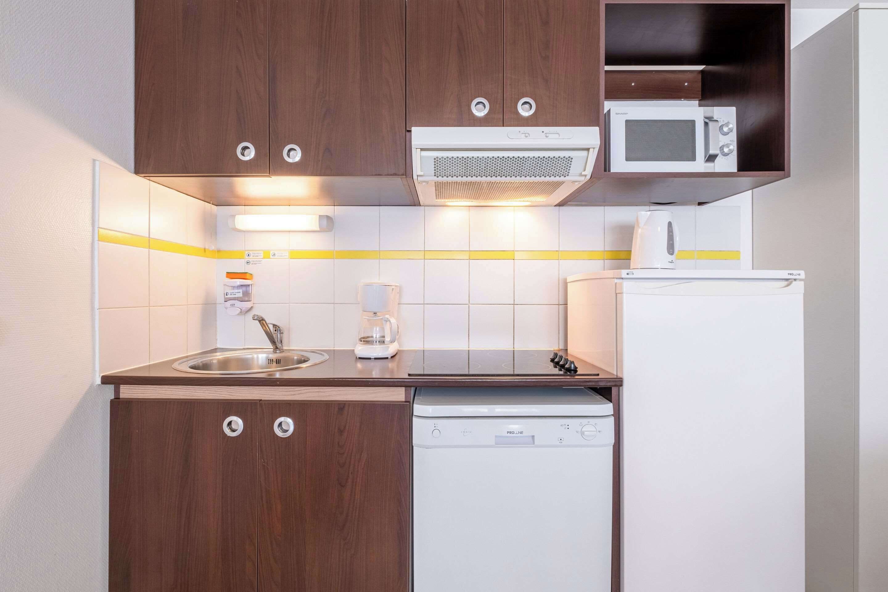 A compact kitchen with a built-in microwave, coffee maker, and dishwasher.