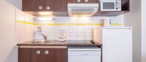 A compact kitchen with a built-in microwave, coffee maker, and dishwasher.