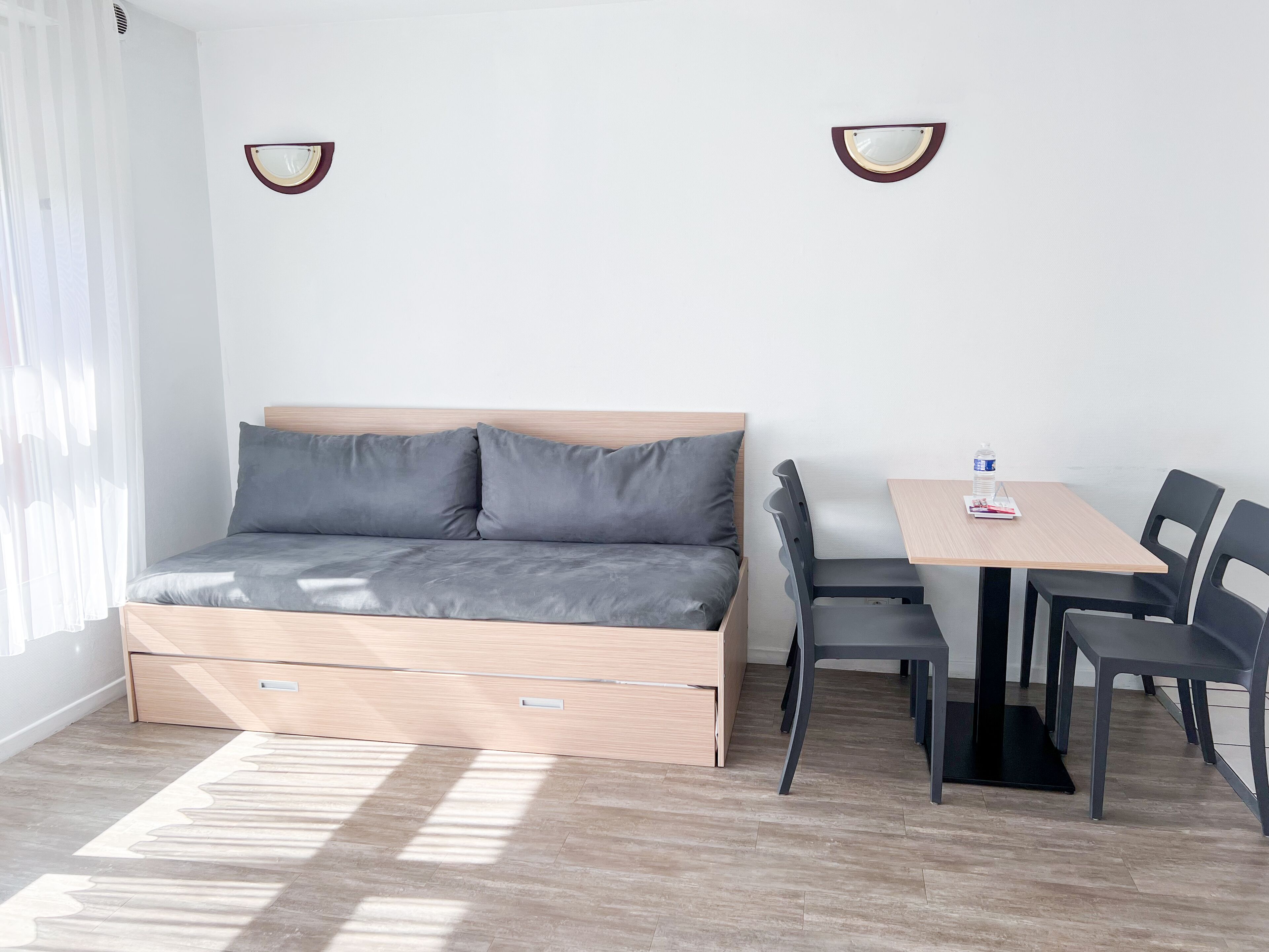 Une petite pièce comprenant un lit, une petite table et deux chaises.