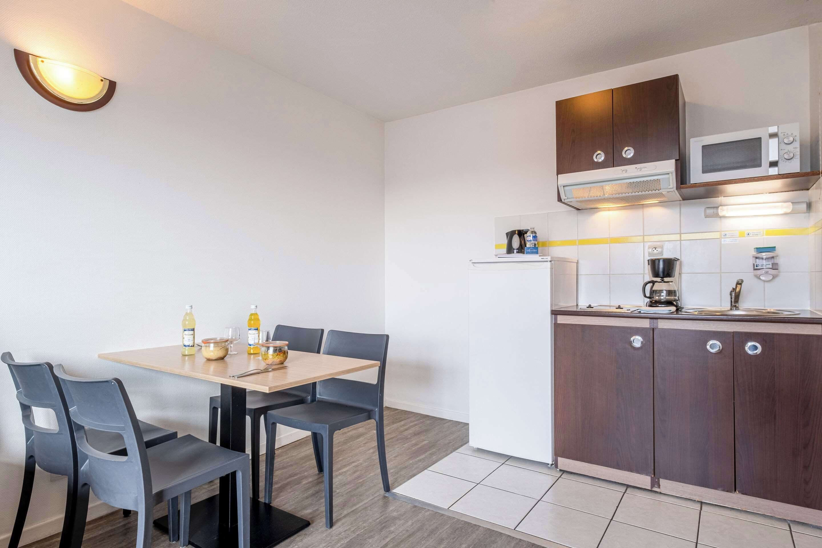 A compact kitchen with a dining area, equipped with a microwave, coffee maker, and a small refrigerator.
