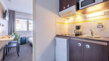 A compact kitchen with a microwave, a coffee maker, and a small refrigerator.