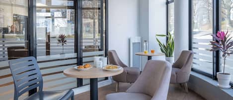 A modern interior with a seating area featuring a round table, chairs, and a potted plant.