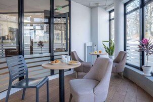 Un interior moderno con una zona de estar que incluye una mesa redonda, sillas y una planta en maceta.
