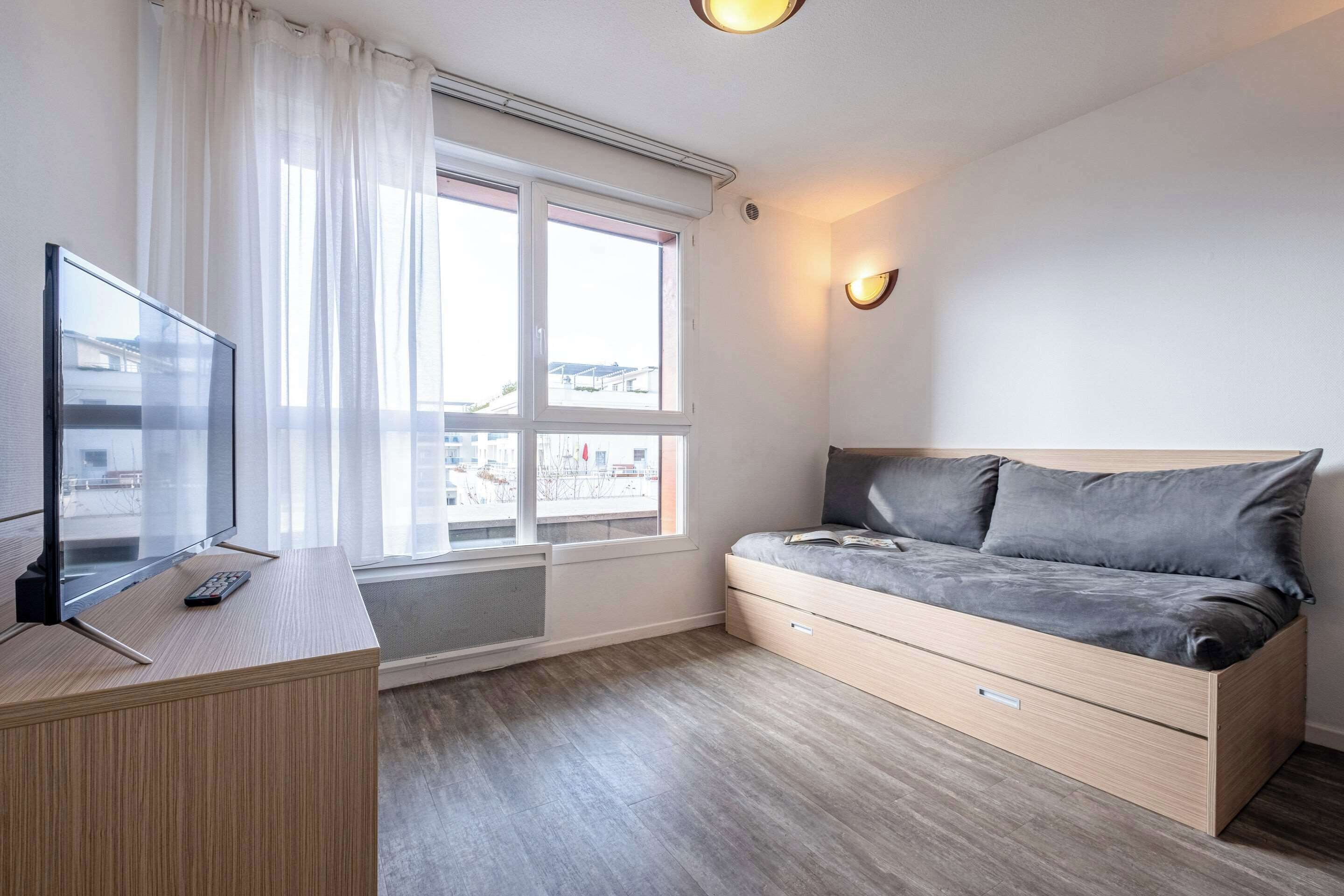 A modern room with a bed, a desk, and a TV.