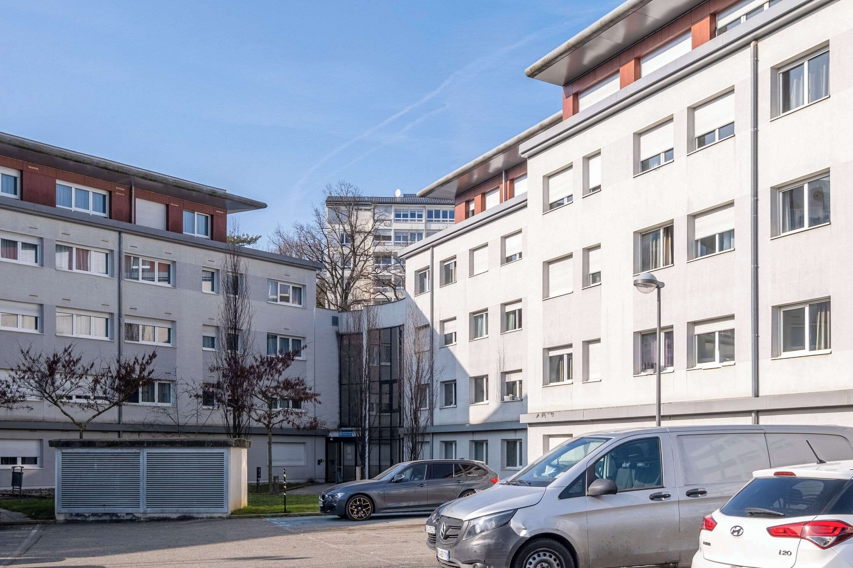 Ein mehrstöckiges Wohngebäude mit Parkplatz davor.